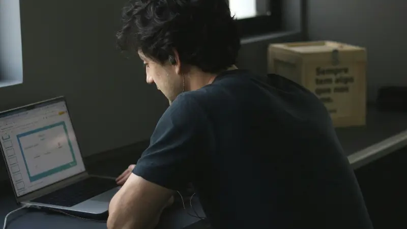 A man works on a laptop in a home office, planning the next steps for his small business